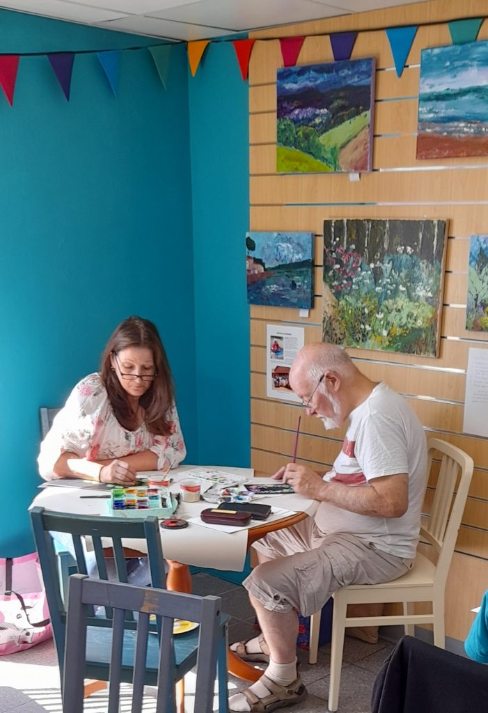 Two people sitting at a table painting