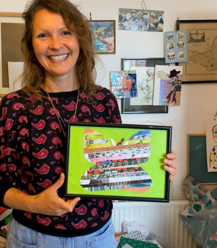 A woman holding a framed crafted picture of a butterfly